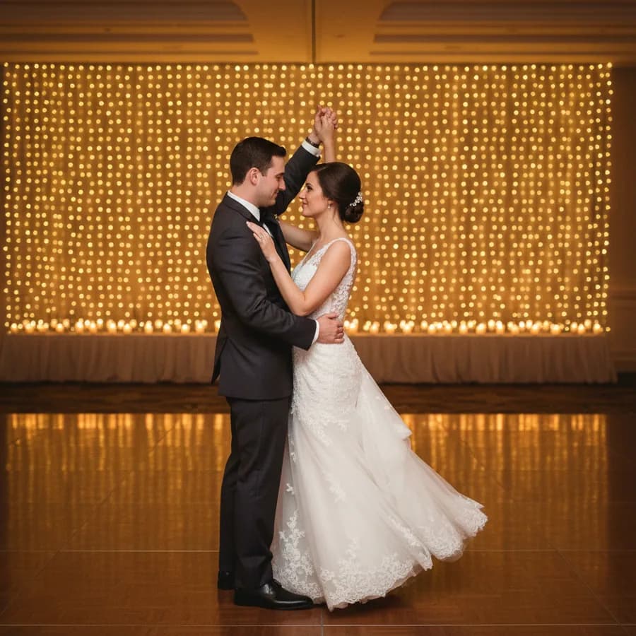 The First Dance — Classic first dance pose. Groom's right hand on bride's waist, left hand holding hers extended. Bride's free hand on his shoulder. They gaze into each other's eyes. Slight sway motion.
